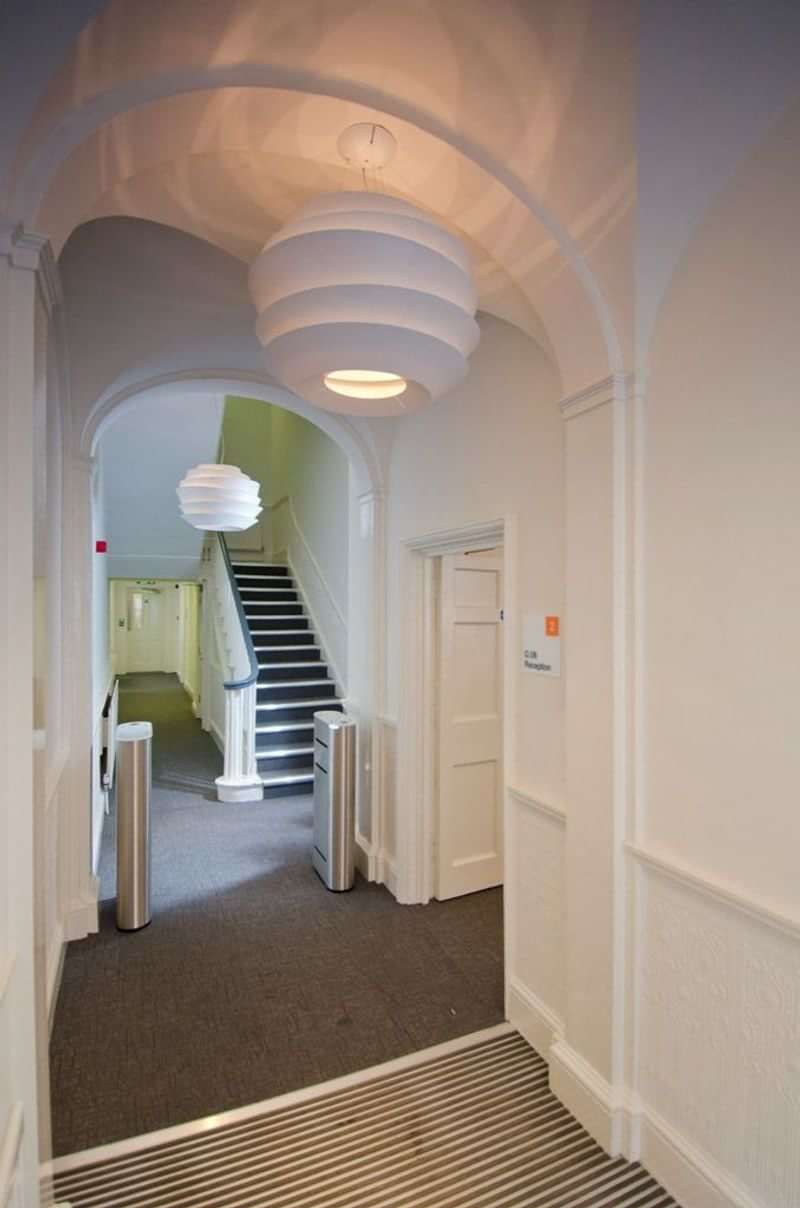 A language school hallway with stairs and modern light fixture.