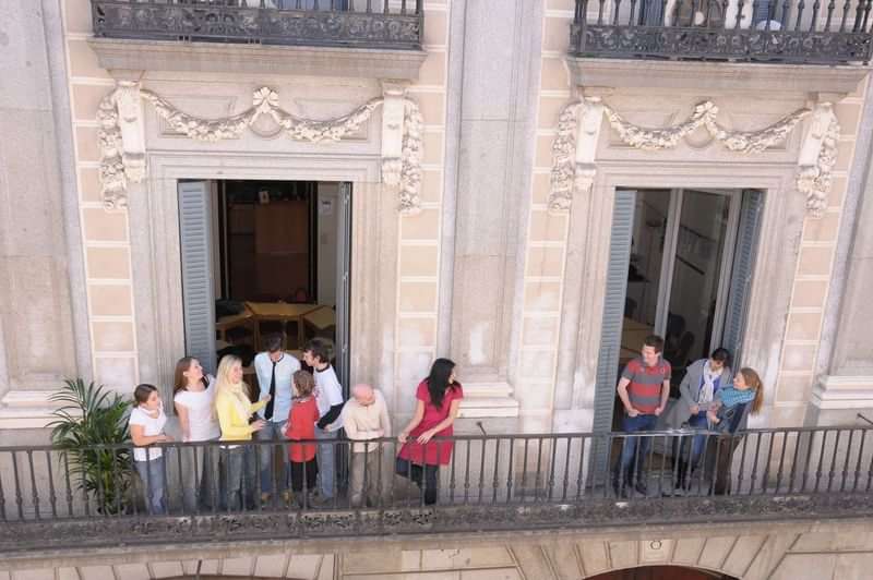 People socializing on balconies of a traditional building, likely language learners.