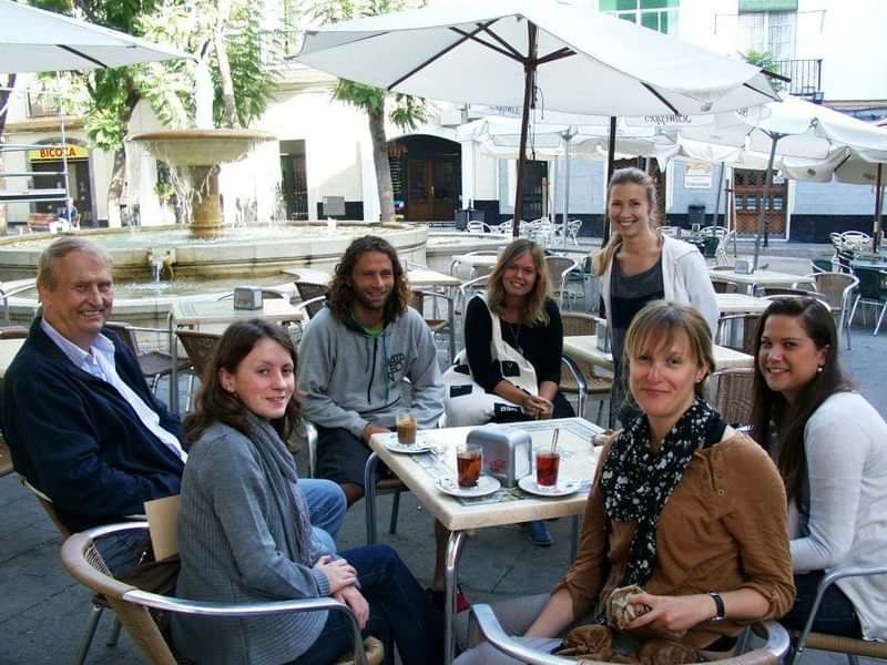 Group of travelers learning languages, enjoying drinks at an outdoor café.