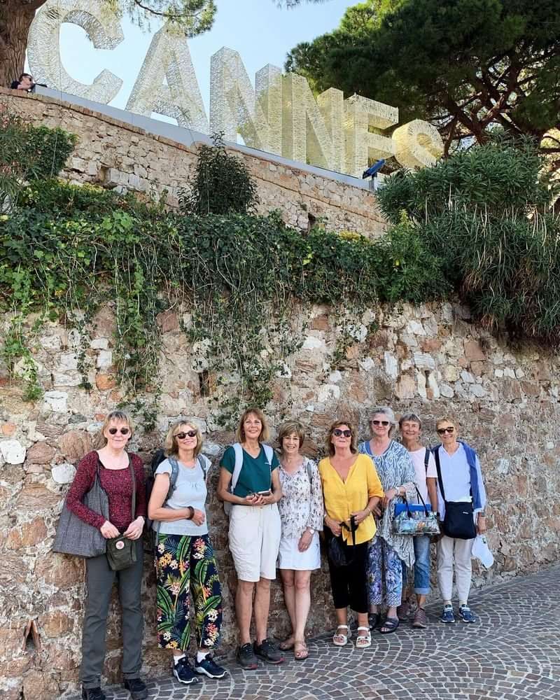 Groep toeristen in Cannes, Frankrijk, poseren voor een stenen muur.