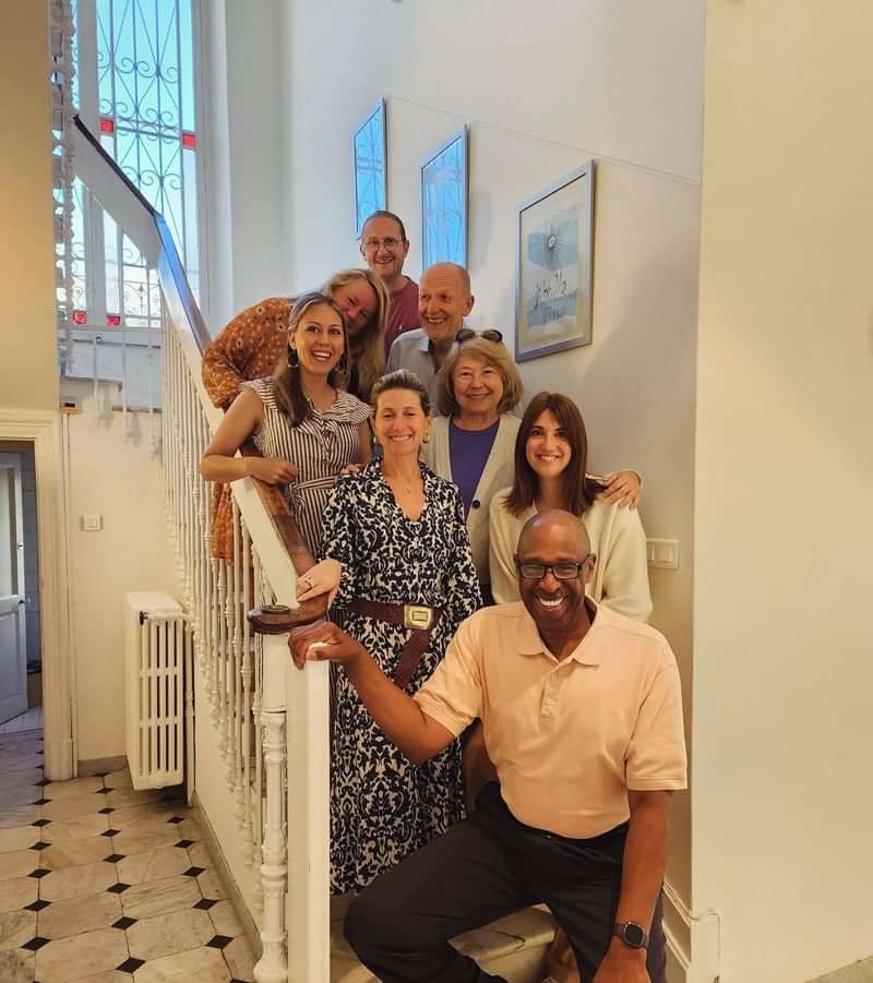Group of language travelers posing on a staircase smiles warmly.