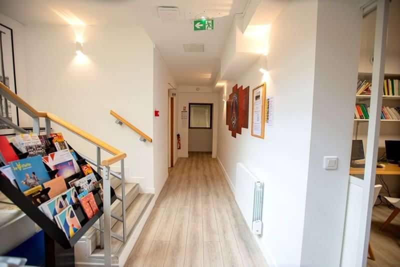 Language school hallway with brochures, bookshelves, stairway, and educational decor.