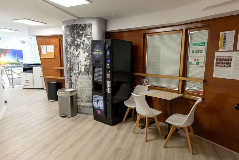 A language school lounge with a vending machine and seating area.