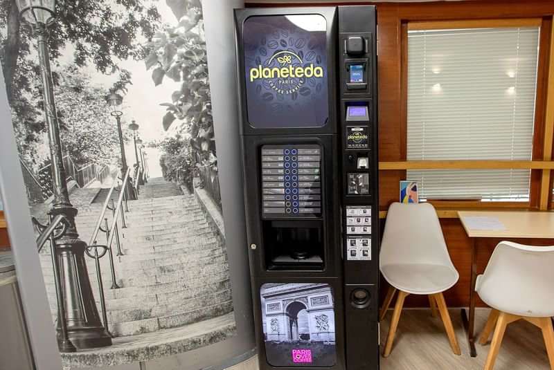 Snoepautomaat naast zitgedeelte en zwart-wit muurschildering van een trap.