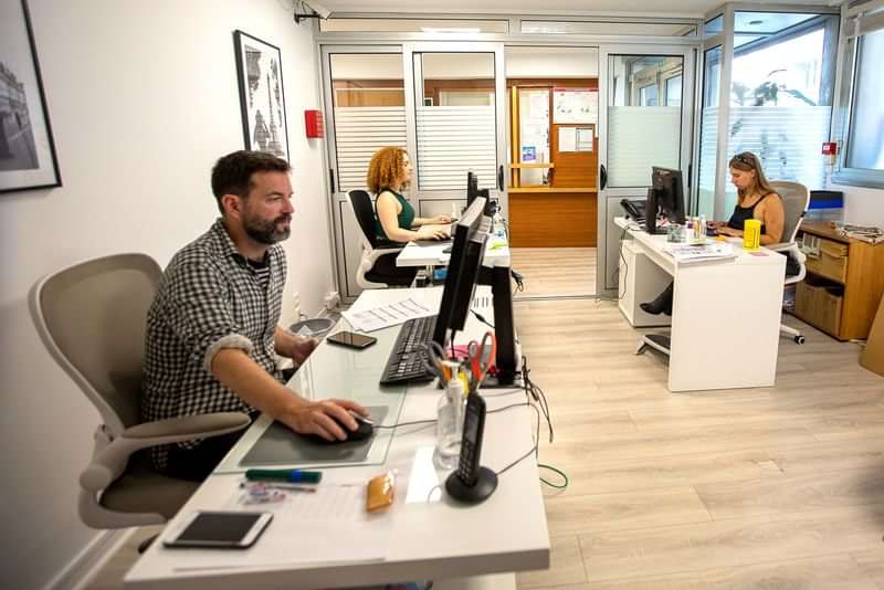 Mensen werken op kantoor bij een taalschool of reisbureau.