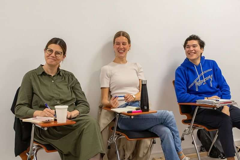 Students in a language class, smiling and taking notes.