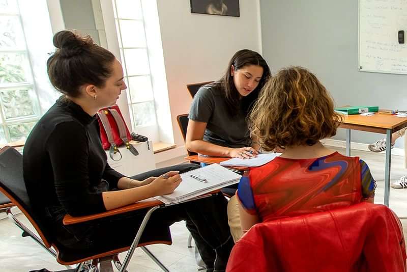 Drie vrouwen die een taalles in een klaslokaal volgen.
