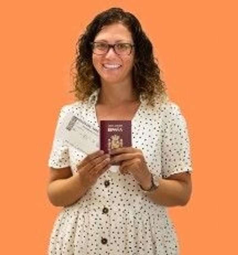 Smiling person holding a passport and a boarding pass, ready to travel.