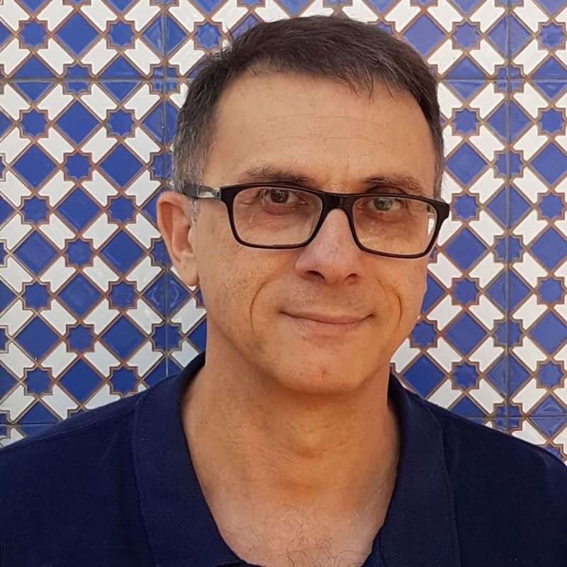 Language teacher in front of traditional patterned tiles, cultural immersion.