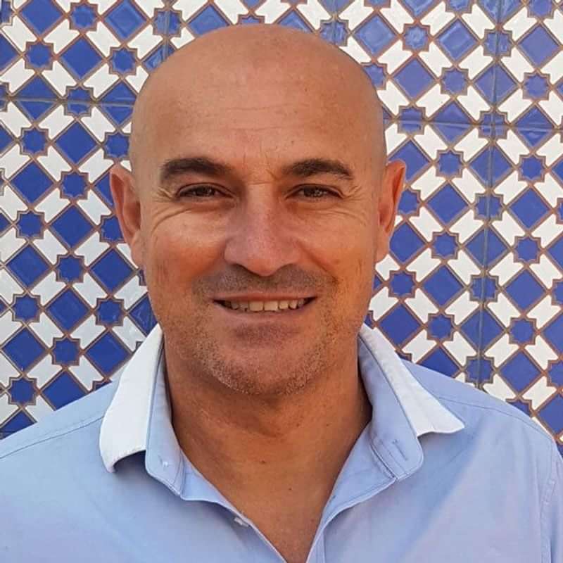 Man standing in front of a tile wall, likely a travel guide.