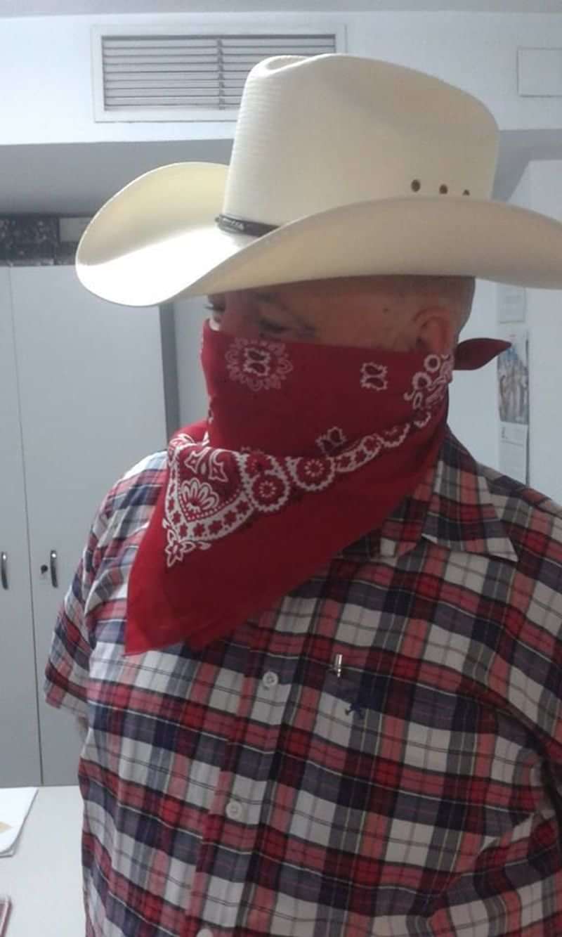 Person with red bandana covering face, wearing plaid shirt, perhaps mimicking western style.