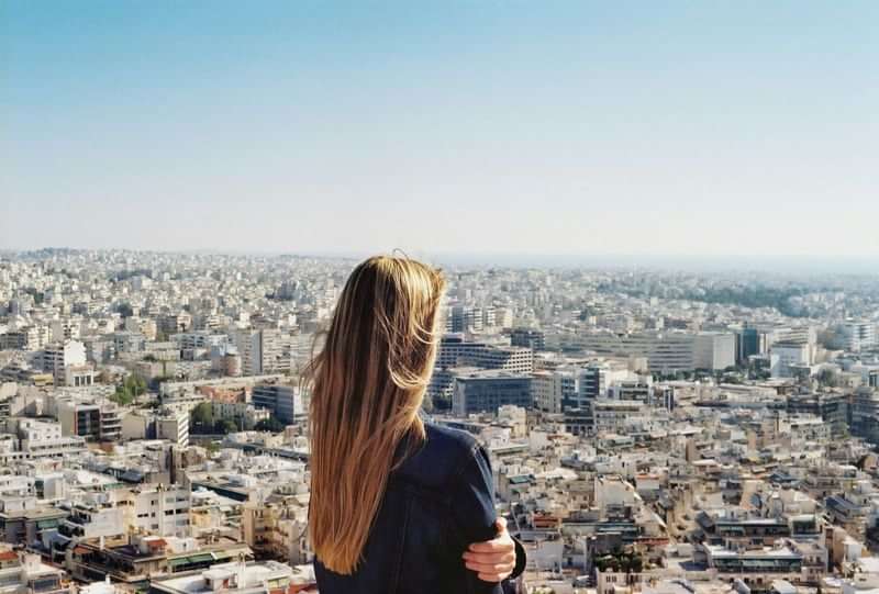Vrouw kijkt uit over stad tijdens taalkundige reiservaring.