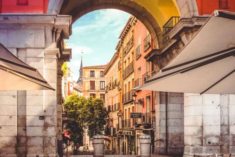 Prachtige Spaanse straat onder een stenen boog, kleurrijke gebouwen.