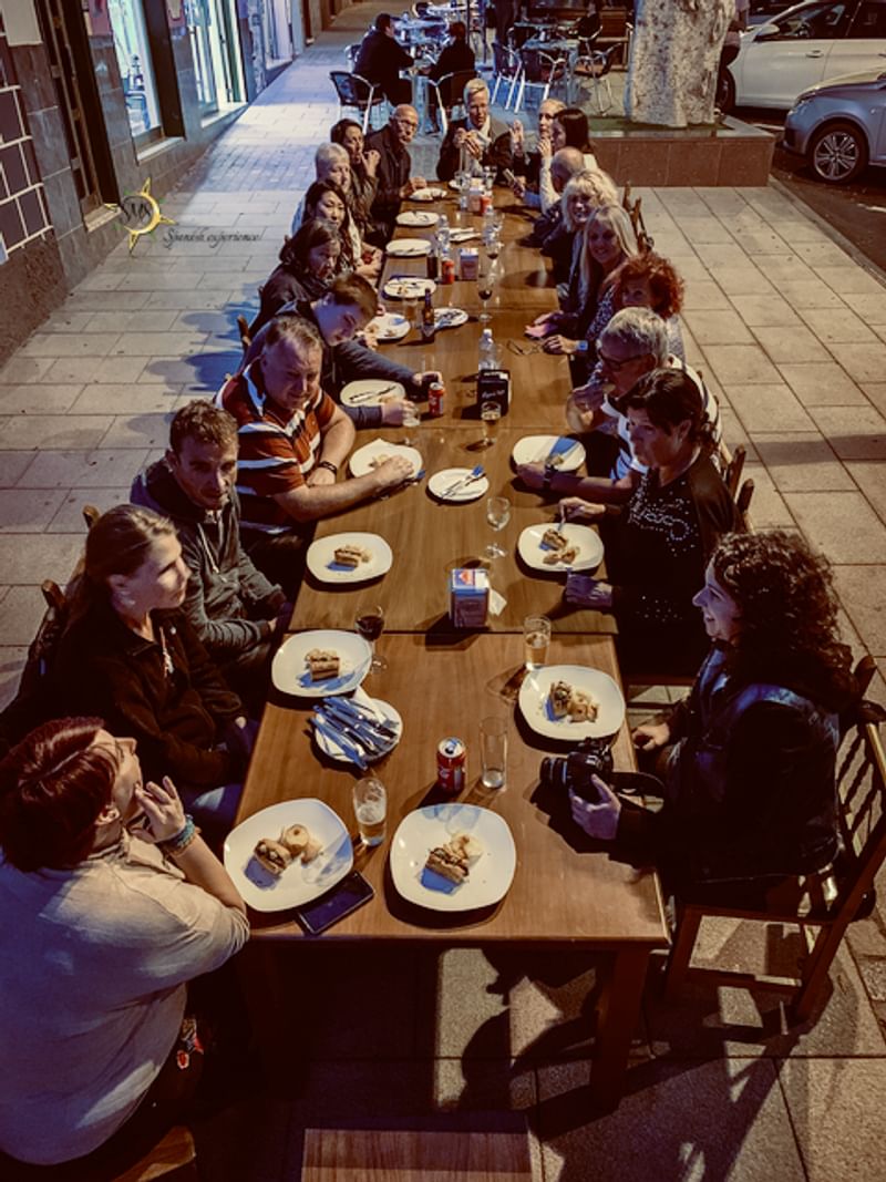 Groep mensen dineren samen buiten tijdens een talige reiservaring.