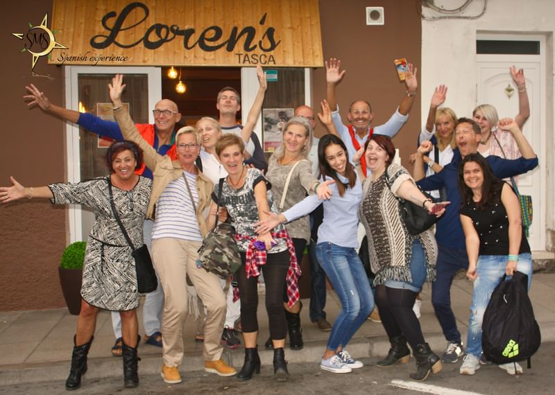 Group of travelers posing happily outside a restaurant, Loren's Tasca.