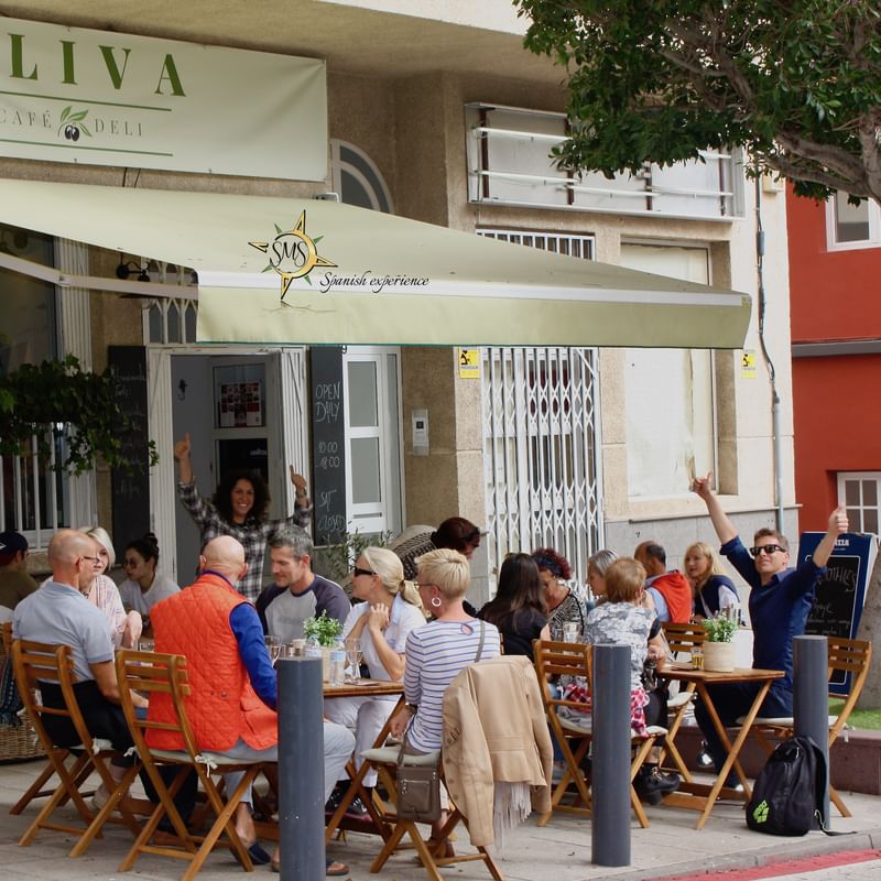 People enjoying a meal at an outdoor café, practicing language skills.