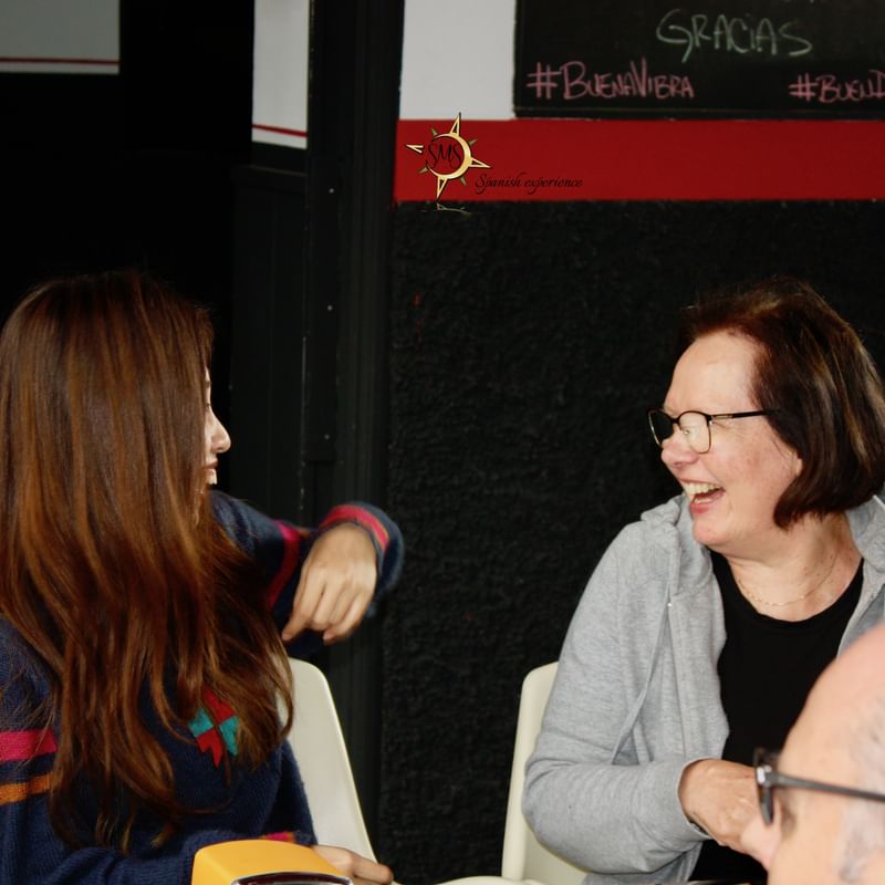 Twee lachende vrouwen in gesprek tijdens een taalreis in Spanje.