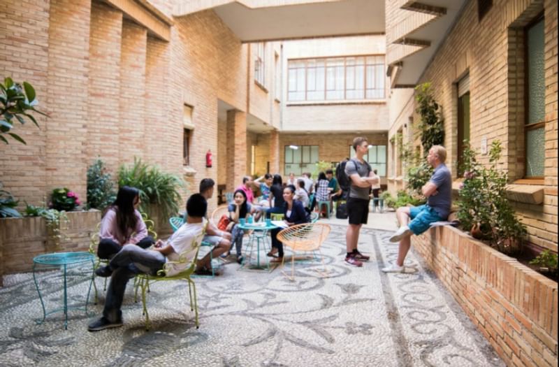 Studenten ontspannen en praten buitenshuis tijdens een taalcursus in het buitenland.