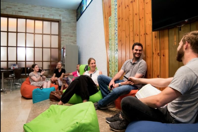 Group relaxing on bean bags, possibly participating in a language exchange program.