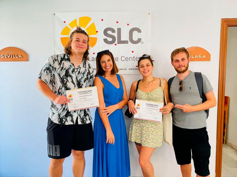 Studenten ontvangen hun certificaat bij taalschool, trots poseren voor foto.