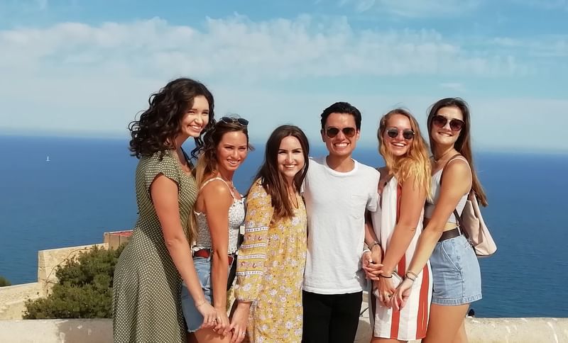 Groep vrienden poseert bij zee tijdens taalreis in Nederland.