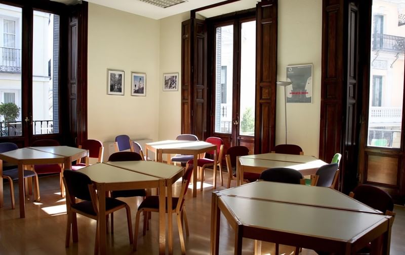 Een leslokaal in een taalinstituut met tafels en stoelen.
