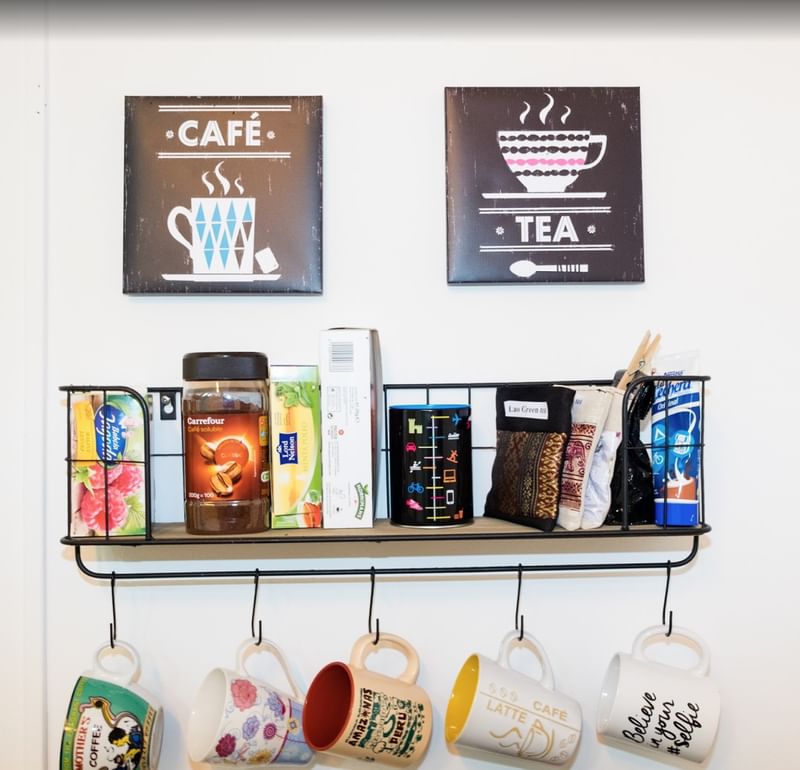 Koffie- en theebenodigdheden op een keukenplank, decoratieve kunst aan de muur.