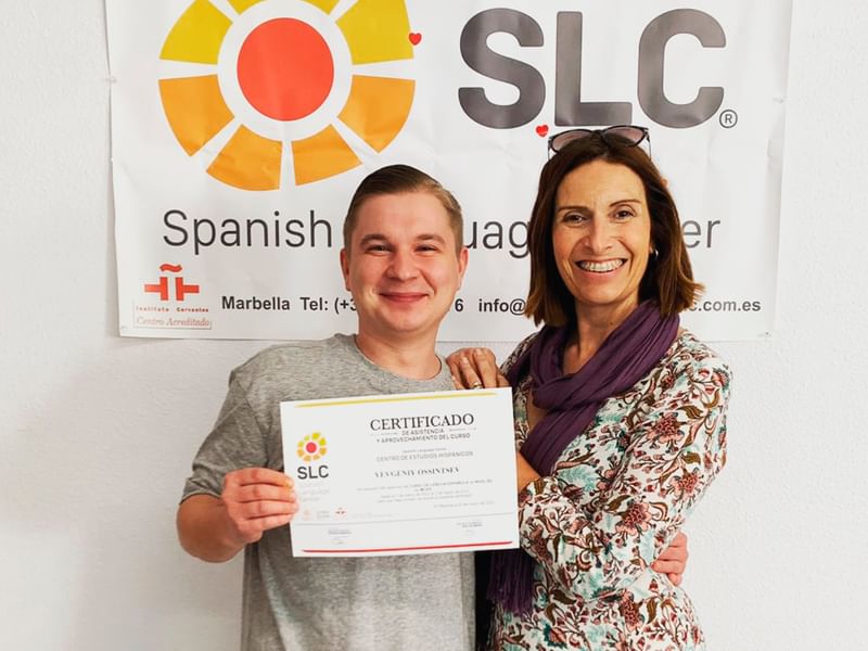 Twee mensen vieren het behalen van een Spaanse taalcursus certificaat.