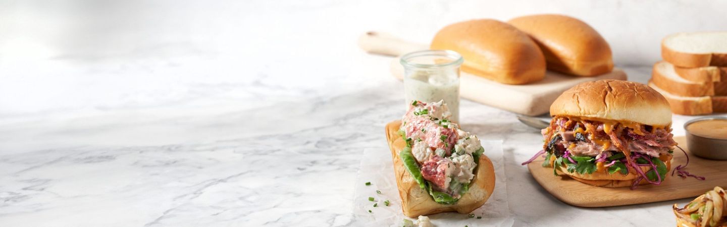 Collage of crab roll, BBQ sandwich, King's Hawaiian sub rolls and sliced bread in background.