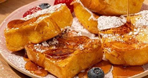 King's Hawaiian french toast drizzled with sryup and fresh fruit on light pink plate							