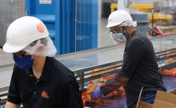 Two line workers packing King's Hawaiian rolls.