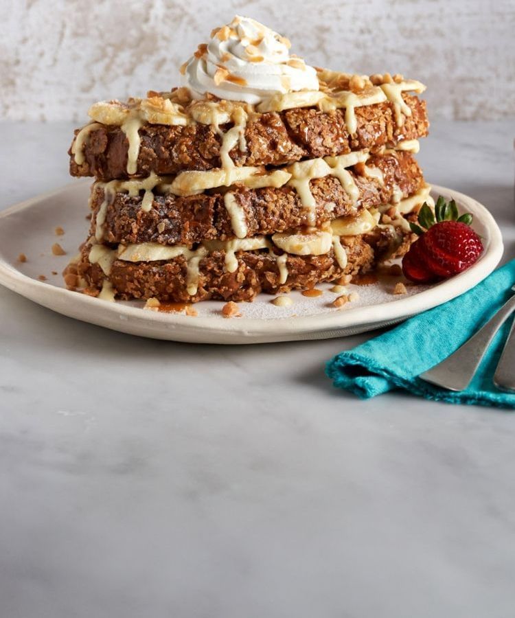 Bananas Foster French Toast on white plate with light background and surface