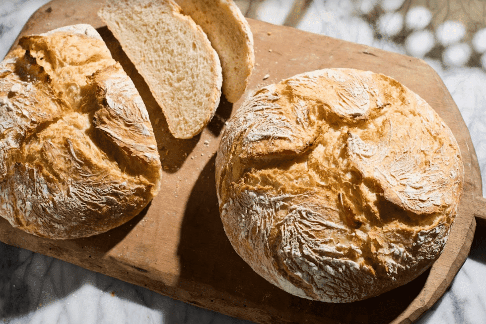 Pão caseiro, dois pães em forma de trança sobre madeira e uma toalha de  mesa quadriculada vermelha e branca, uma faca e um ramo de trigo.
