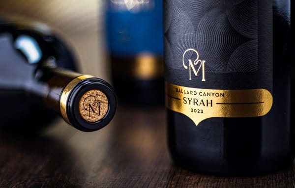 Close up of a bottle of MarAmi Syrah next to another bottle on its side