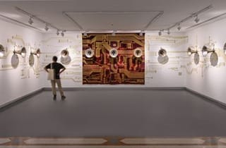 <span class="artist">Khadim Ali</span><span class="title"> Khadim Ali in collaboration with Sher Ali, Urbicide. From &#039;Flowers of Evil&#039;</span><span class="year"> 2019</span>, <span class="medium">11-channel sound: steel, metal, gold leaf; nylon thread on machine, woven rug</span>, <span class="dimen dimen-notes">Dimensions variable</span>, <span class="notes">Installation view: Sharjah Biennial 14: ‘Leaving the Echo Chamber’ 2019. Commissioned by Sharjah Art Foundation. Courtesy of the artist. Courtesy of Sharjah Art Foundation</span>