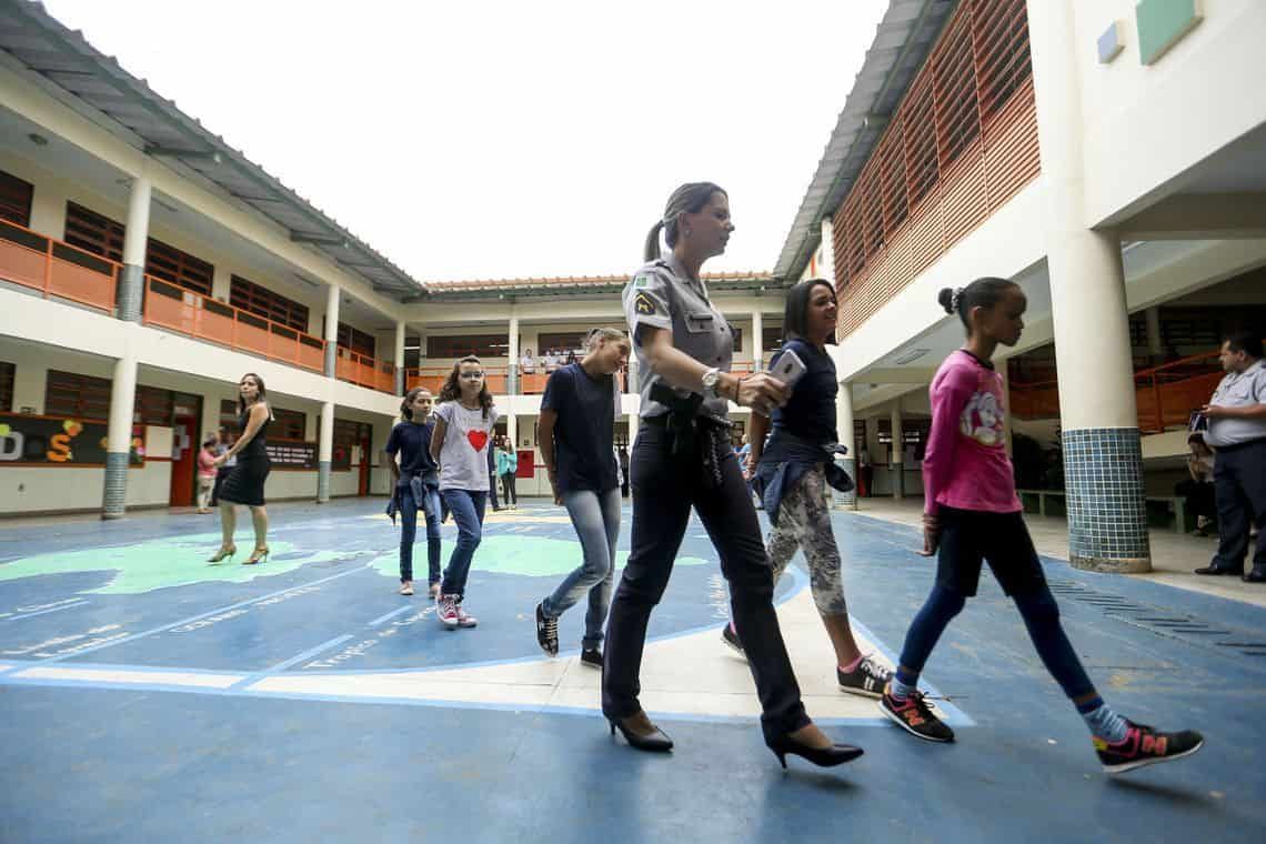 Alunos e educadores andam pelo pátrio de uma escola cívico-militar
