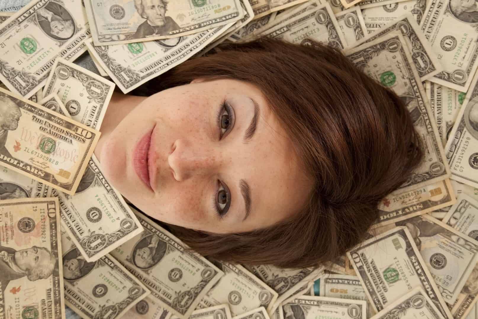 mulher imersa em notas de dinheiro