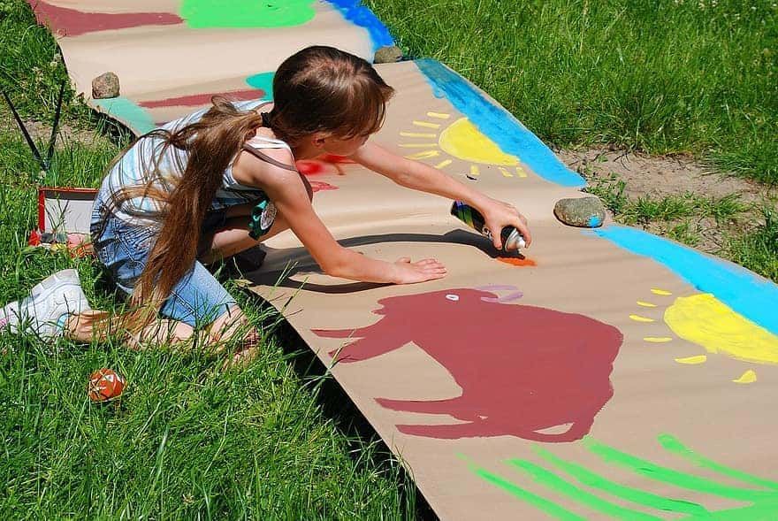 Criança pintando mural com tinta spray. A pintura é uma das habilidades que o seu filho pode ter quando pequeno.
