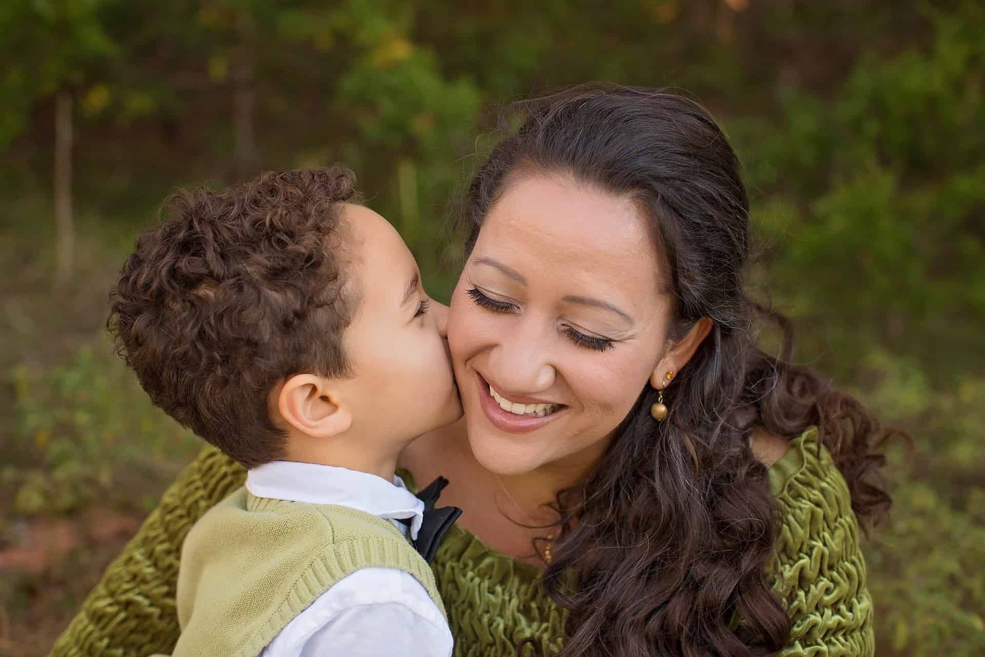 Foto mostra um menino pequeno beijando a sua mãe na bochecha. O afeto é um dos pilares da disciplina positiva, abordagem que visa educar de maneira firme e gentil.