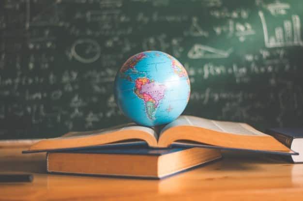 Imagem de um globo terrestre em cima de um livro, simbolizando a educação. Entre os países que mais investem em educação no mundo, Brasil gasta menos da metade por aluno comparado a países de primeiro mundo.