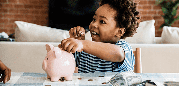 Menino depositando moeda no porquinho. Essa é uma ótima maneira de ensinar a educação financeira para crianças.