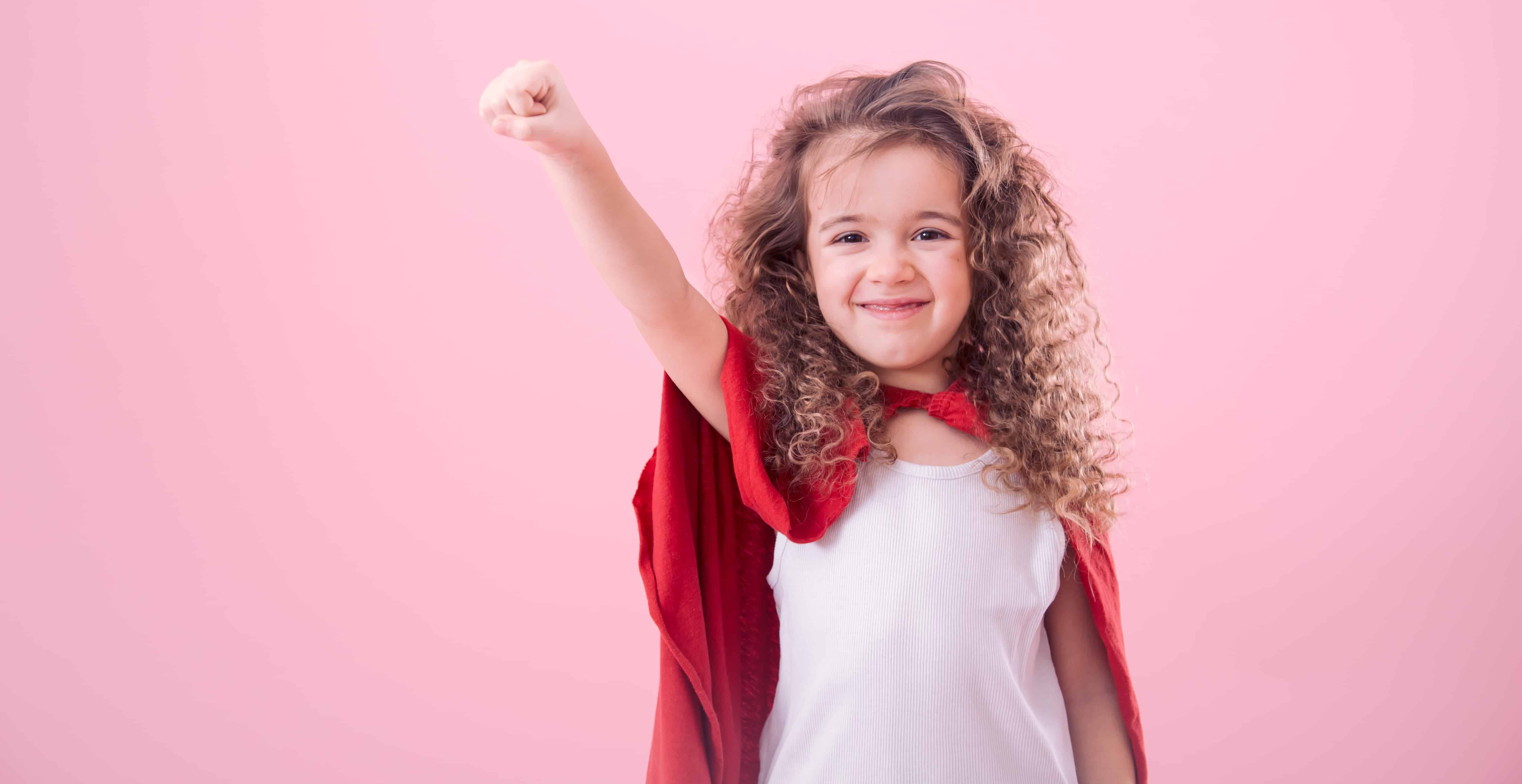 Menina vestida de superheroína, mostrando que a presença de personagens femininas nos desenhos infantis podem contribuir para a autoestima e autoconfiança das meninas