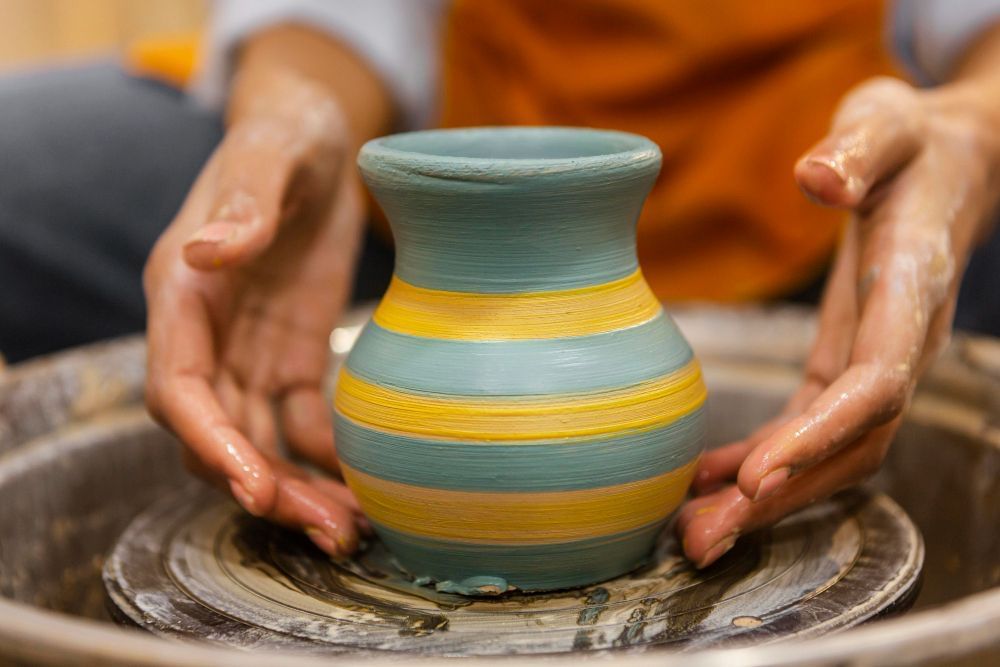 Pessoa realizando trabalho de cerâmica com vaso feito de argila. 