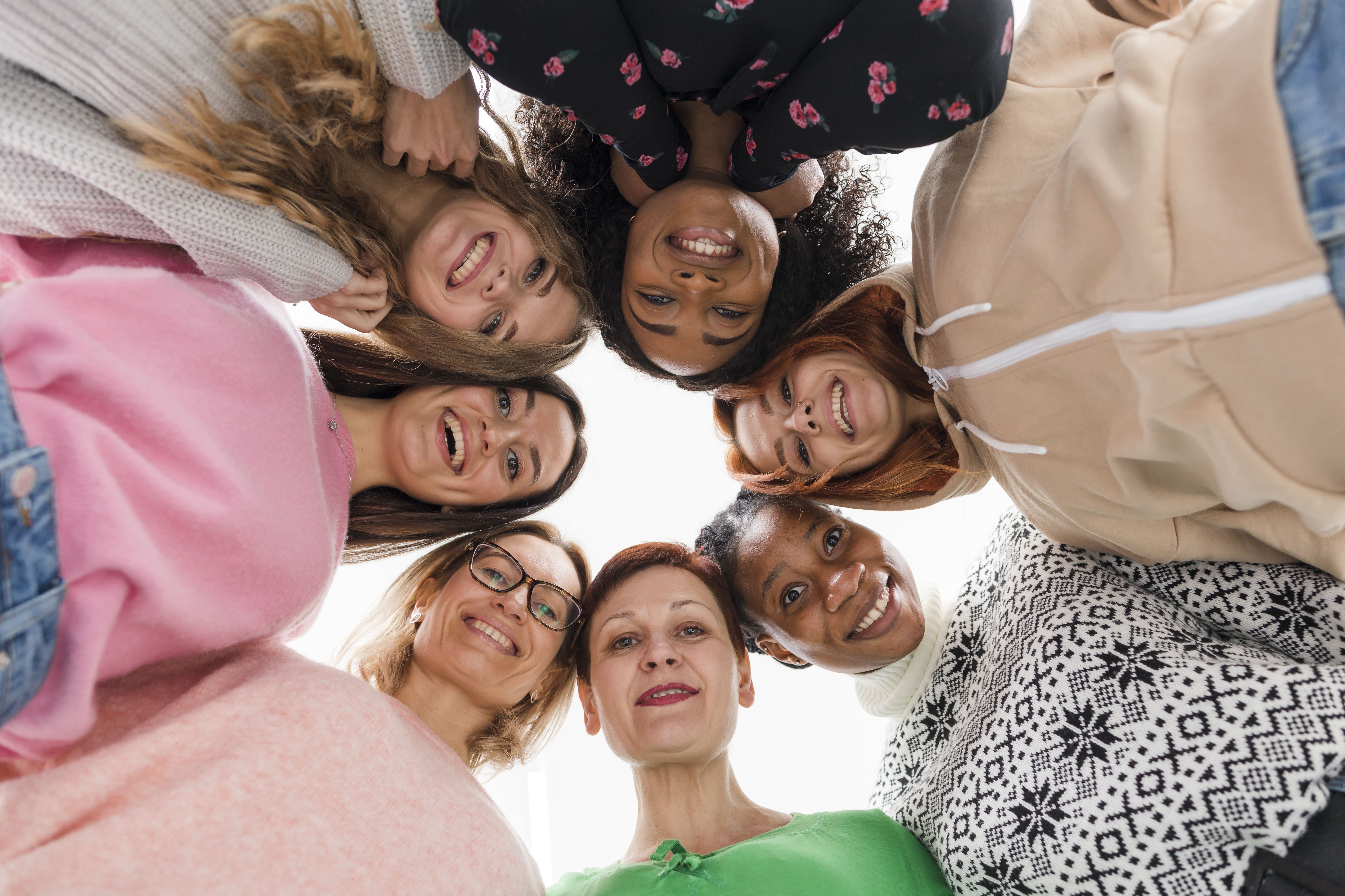 Círculo de mulheres juntas, abraçadas e olhando para baixo; Mulheres na pós-graduação: perspectivas e desafios