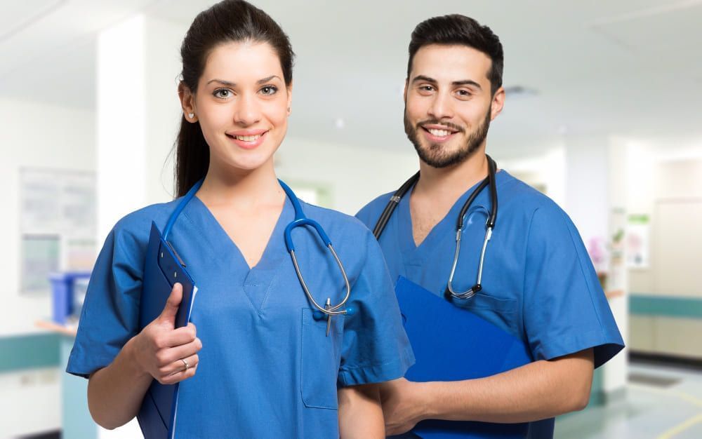 dois enfermeiros, um homem e uma mulher, olhando para a frente e sorrido ; saiba quanto custa um curso técnico em Enfermagem