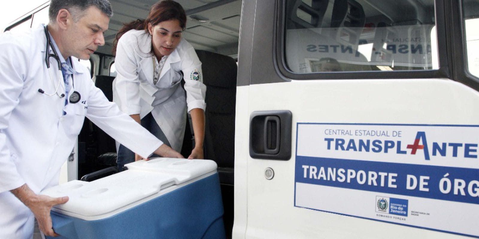 Profissionais da saúde carregam caixa em frente a uma van com o escrito "transporte de órgãos"; veja as profissões que atuam na doação e transplante de órgãos