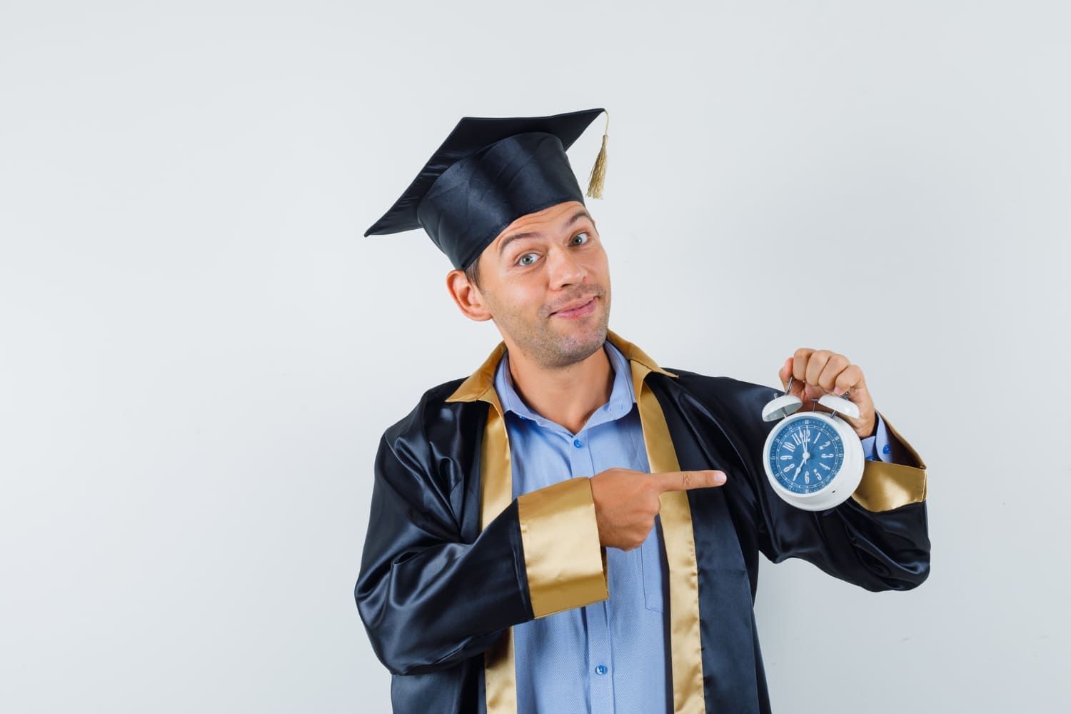 Homem vestindo uma beca de formatura e segurando um relógio na mão; veja as faculdades e cursos de 2 anos de duração mais buscados