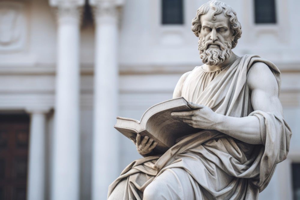 Imagem mostra uma estátua de mármore representando um pensador da antiga Grécia com um livro em mãos