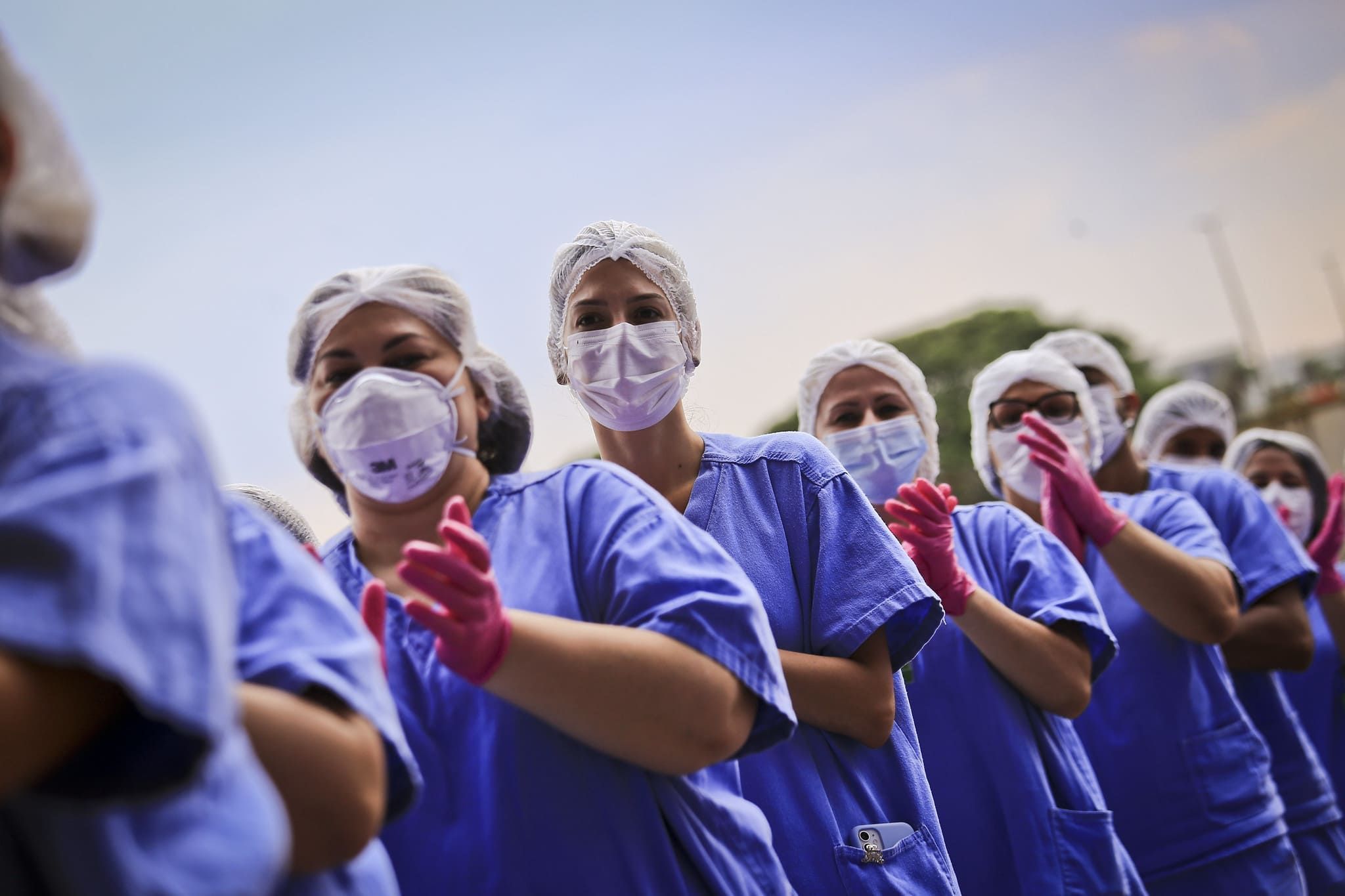 A foto ilustra vários enfermeiros utilizando EPIs (Equipamentos de Proteção Individual)