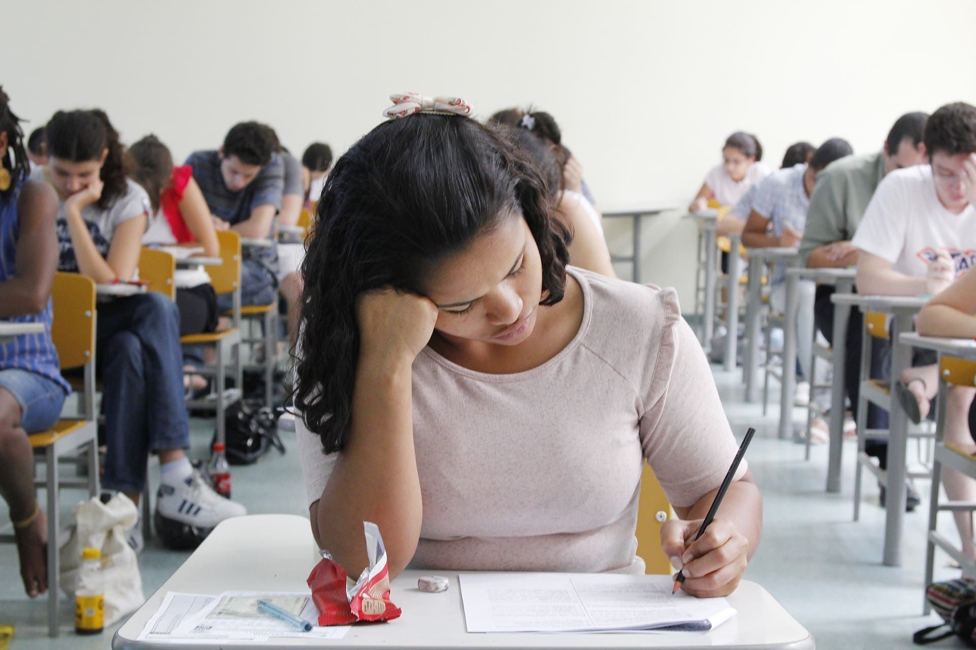 Estudante sentada na carteira fazendo prova; Fuvest 2024: veja horários e o que levar na 2ª fase